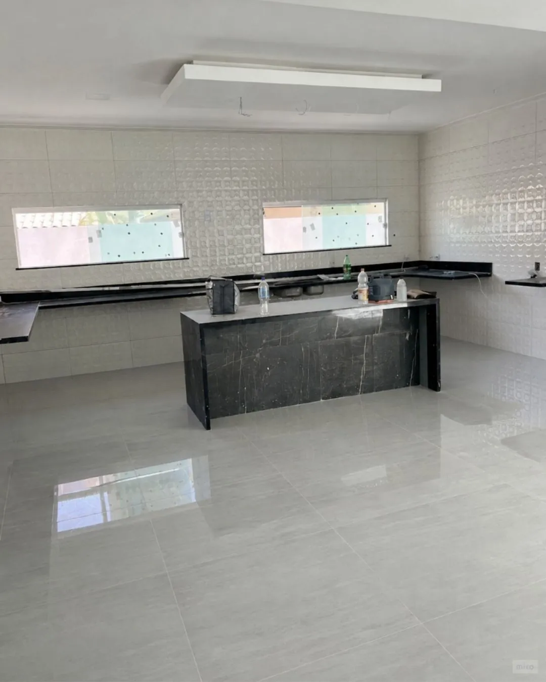 Cozinha com ilha central e bancada em pedra natural, com piso contínuo