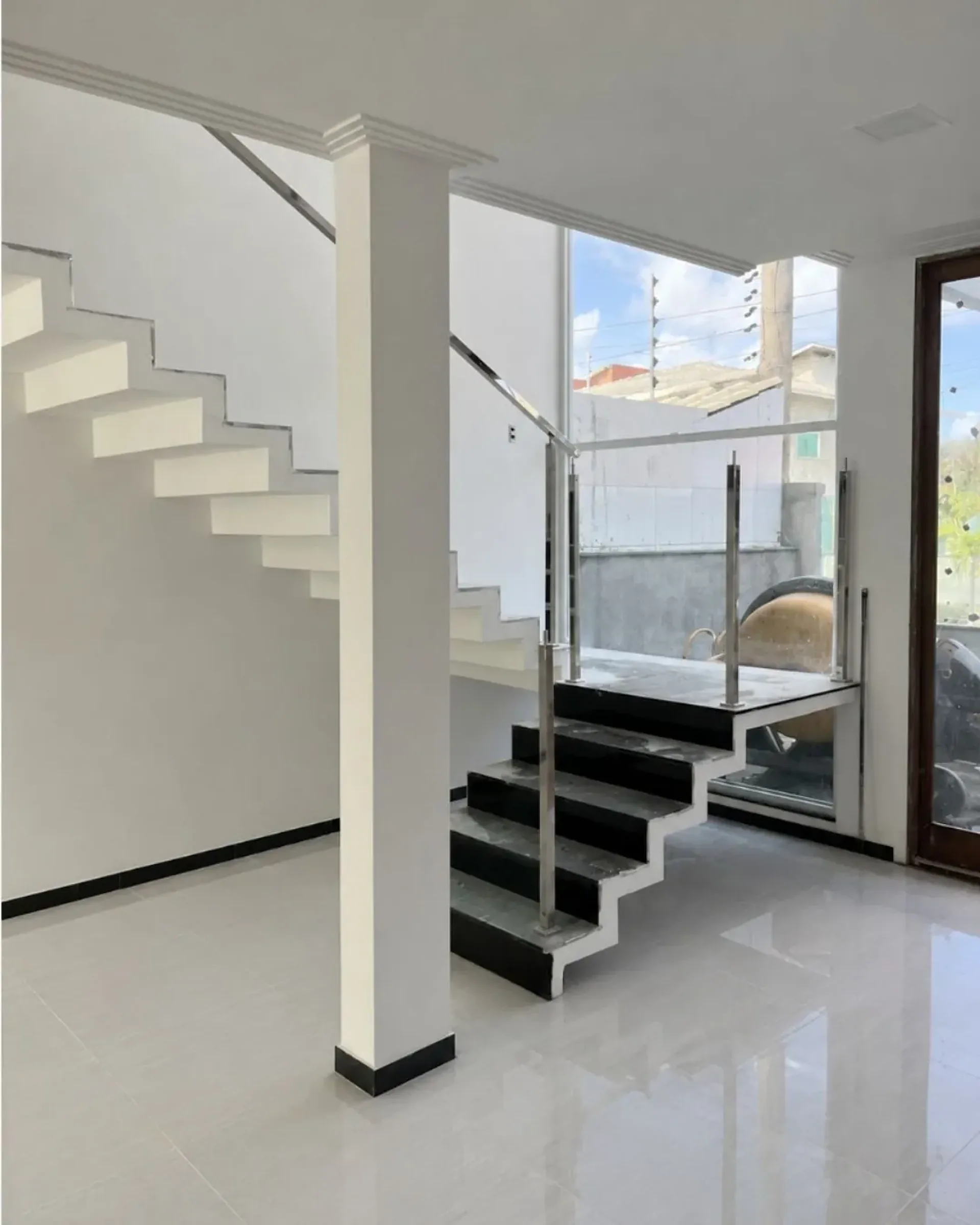 Escada interna entregue pela Pilares, com guarda-corpo de vidro e vista para fora