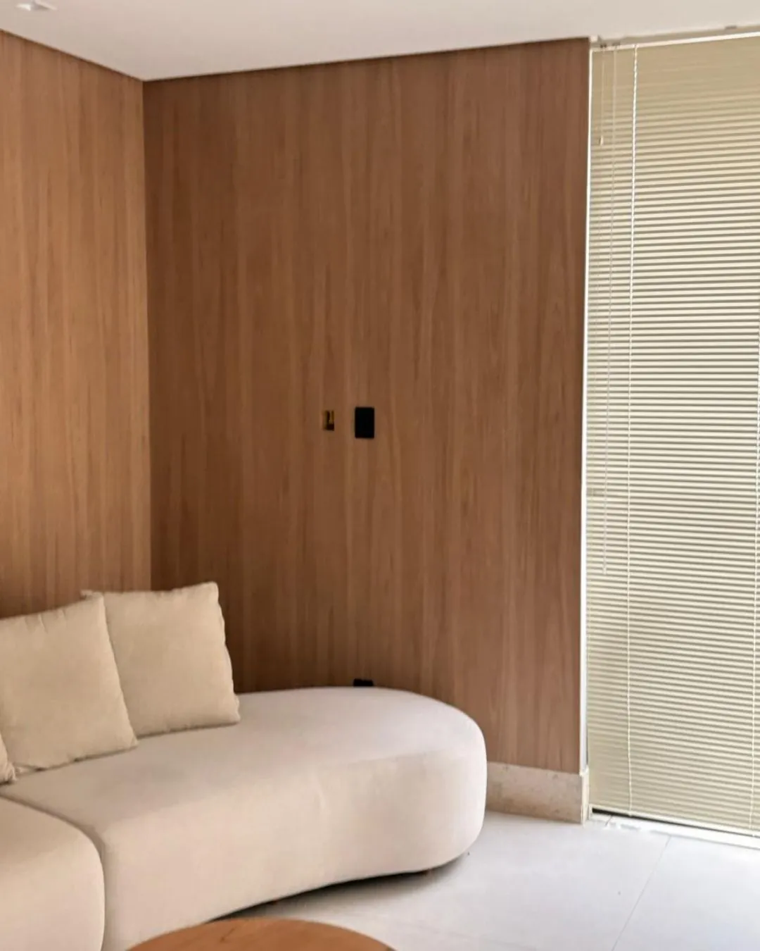 Sala de estar do Apartamento LSP, com painel de madeira e sofá curvo